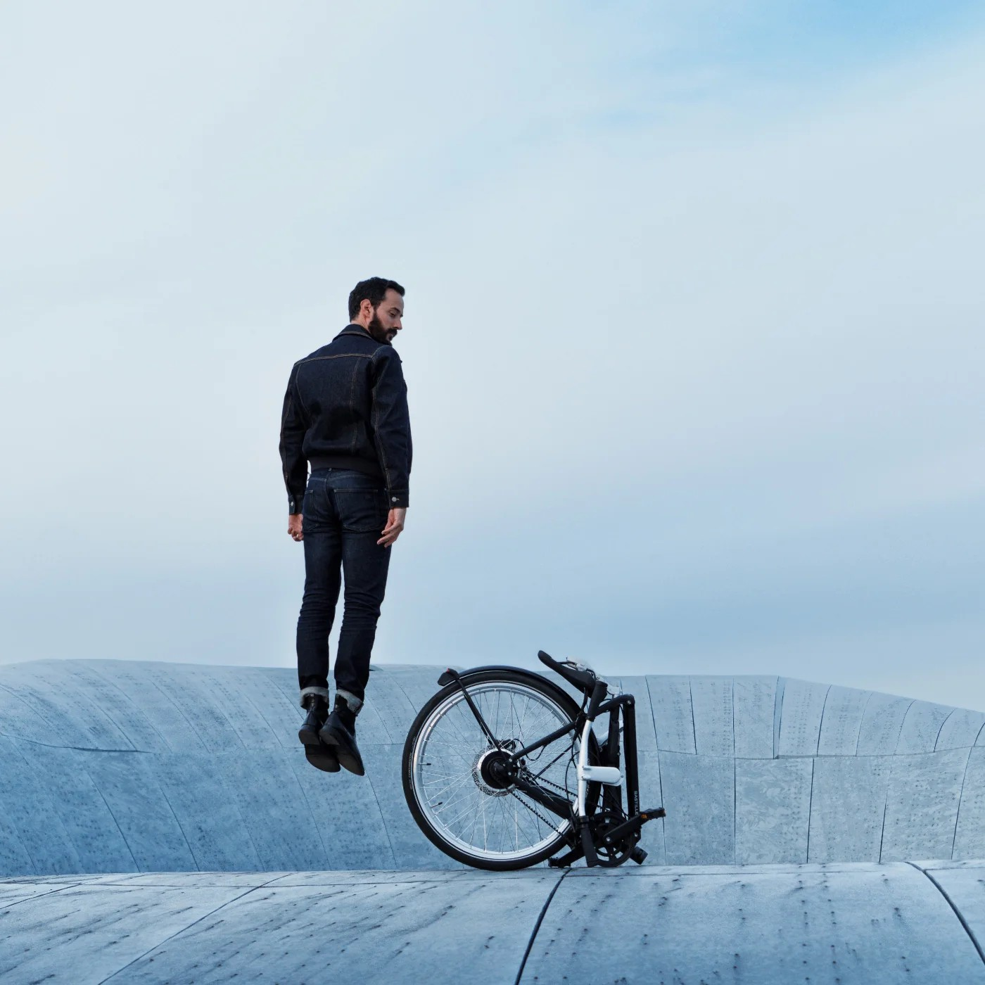 A man jumping besides a Bastille bike.