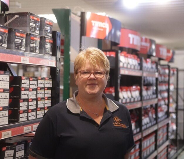 C&C Supplies store manager in front of TIMCO product shelves